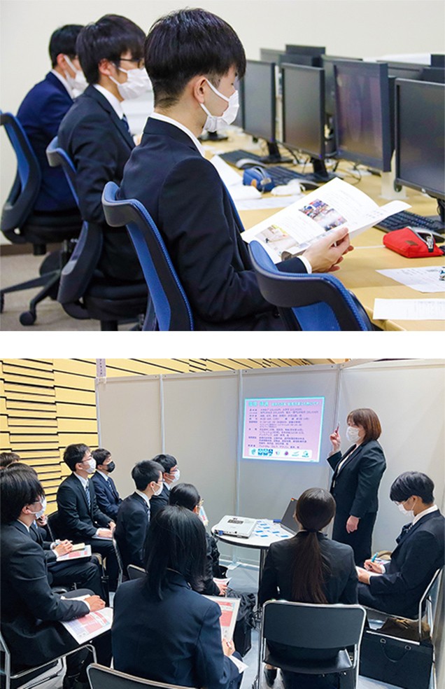 写真：福岡工業大学内で行われている、大学独自の合同企業セミナーの様子。スーツを来た学生が各企業ブースで説明を受けている。